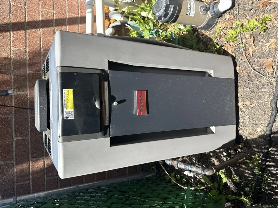 A pool heater beside a brick wall, photographed from the front
